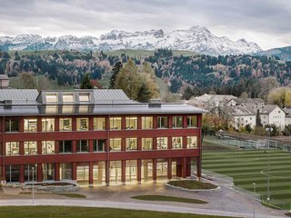 Die Holzfassade in roter Farbe ist in Appenzell seit jeher ein bewährtes Element, die Dachlandschaft mit sechs Lukarnen und integrierten Photovoltaikpaneelen jedoch von neuster Technik. Sie ist mit Zinkblech eingekleidet. 
